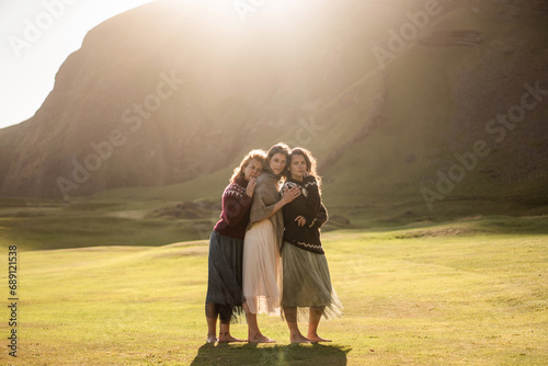 Fototapeta Naklejka Na Ścianę i Meble -  A group of girls tourists in colorful national Icelandic sweaters at sunset 