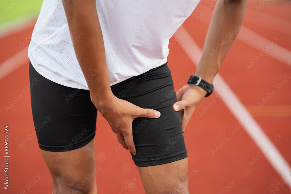 Athletes sport man runner wearing white sportswear to sitting feeling pain in his leg or knee or thigh after practicing on a running track at a stadium, copy space. Runner sport injury concept. - obrazy, fototapety, plakaty 
