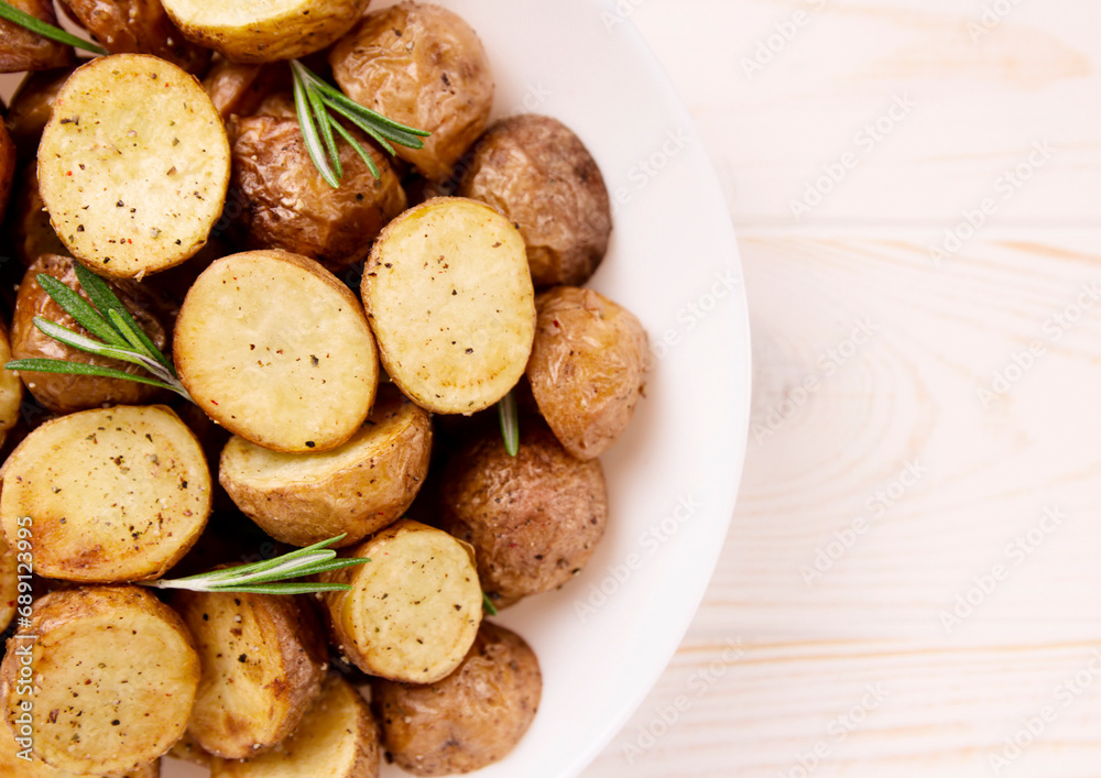 Delicious baked potatoes with rosemary on a light background Delicious baked potatoes with rosemary on a light background
