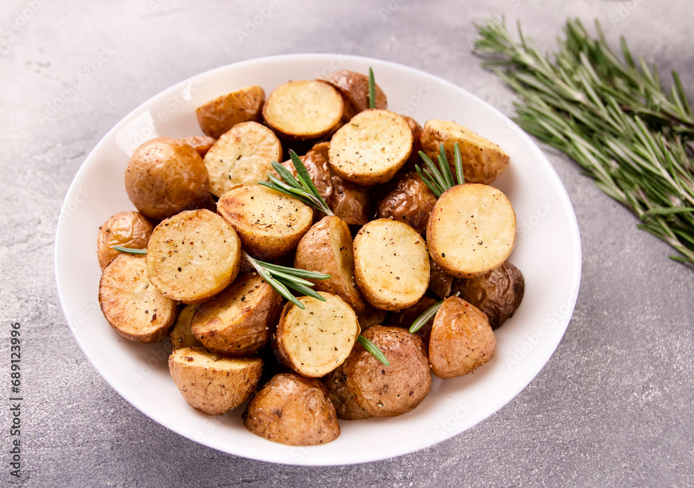 Delicious baked potatoes with rosemary on a gray background Delicious baked potatoes with rosemary on a gray background