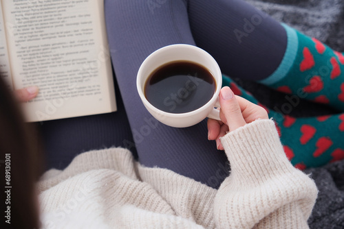 Top view of young brunette woman with coffee and book in hand.Peaceful hours at home with book and coffee.