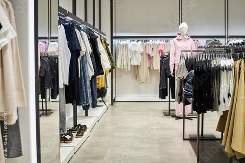 Wide shot of modern clothing store interior with garments for sale hanging on racks © AnnaStills
