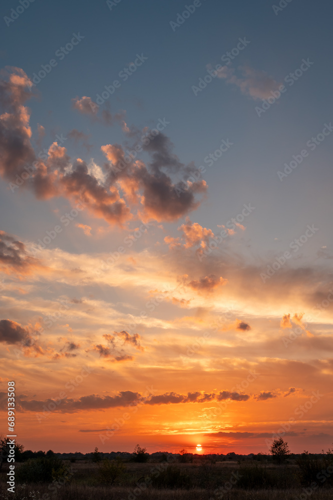 Colorful cloudy sunset over the field. Nature in countryside, vibrant sunset above the horizon