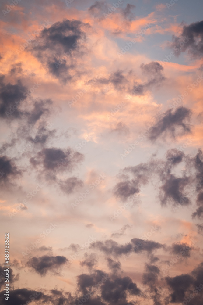 Colorful clouds in sky during sunset. Vertical shot of bright vibrant clouds in evening sky