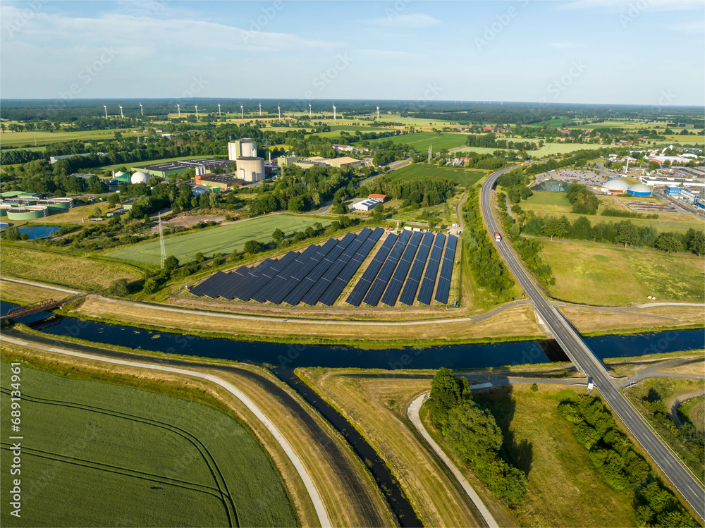 Drone Shot of solar panels at a sunny day between fields, river and a street. Drone Shot of solar panels at a sunny day between fields, river and a street.