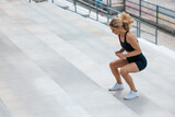 Blonde woman in sportswear jumping on the stairs