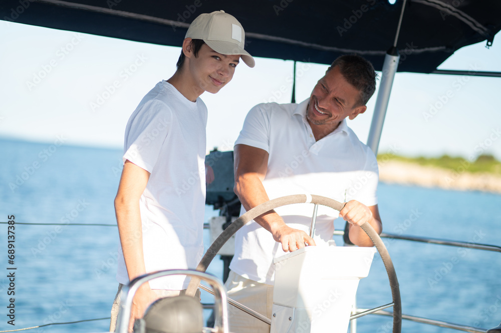 Dad showing his son how to manage the boat