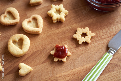 Filling handmade Linzer Christmas cookies with strawberry marmalade