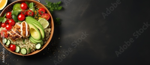 Grilled chicken quinoa spinach avocado brussels sprouts tomatoes cucumbers in a healthy buddha bowl viewed from the top on a dark gray background Copy space image Place for adding text or desig photo