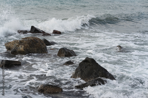Stone breakwater on the Mediterranean coast, small waves near the coastline. Rolling waves crashing