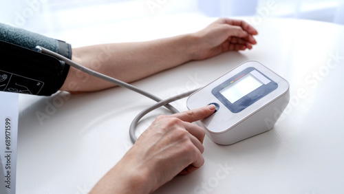 A GIRL WITH A BLOOD PRESSURE MONITOR MEASURES BLOOD PRESSURE