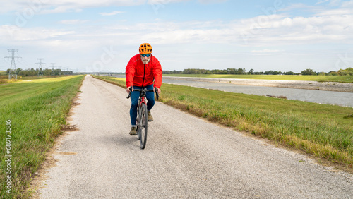 senior athletic man is riding a gravel touring bike - biking on a levee trail along Chain of Rocks Canal near Granite City in Illinois