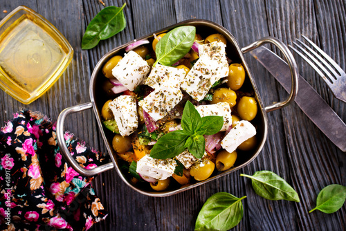 feta cheese with olives and olive oil sauce in bowl on dark background.