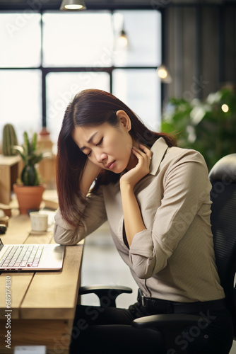 Young tired Asian woman with neck pain sits at the computer. Sad, unhappy, worried, depressed or stress concept in employee life photo