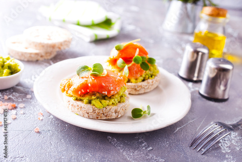 open sandwiches with rye bread, avocado, smoked salmon on a white plate