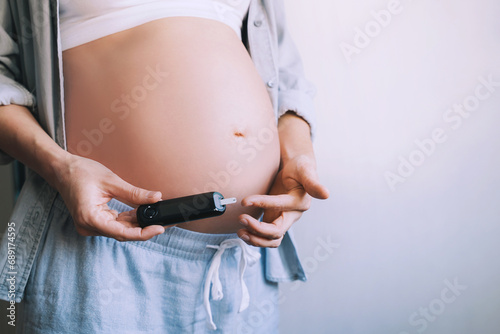 Gestational diabetes test during pregnancy. Pregnant woman checking blood sugar level with glucometer. photo