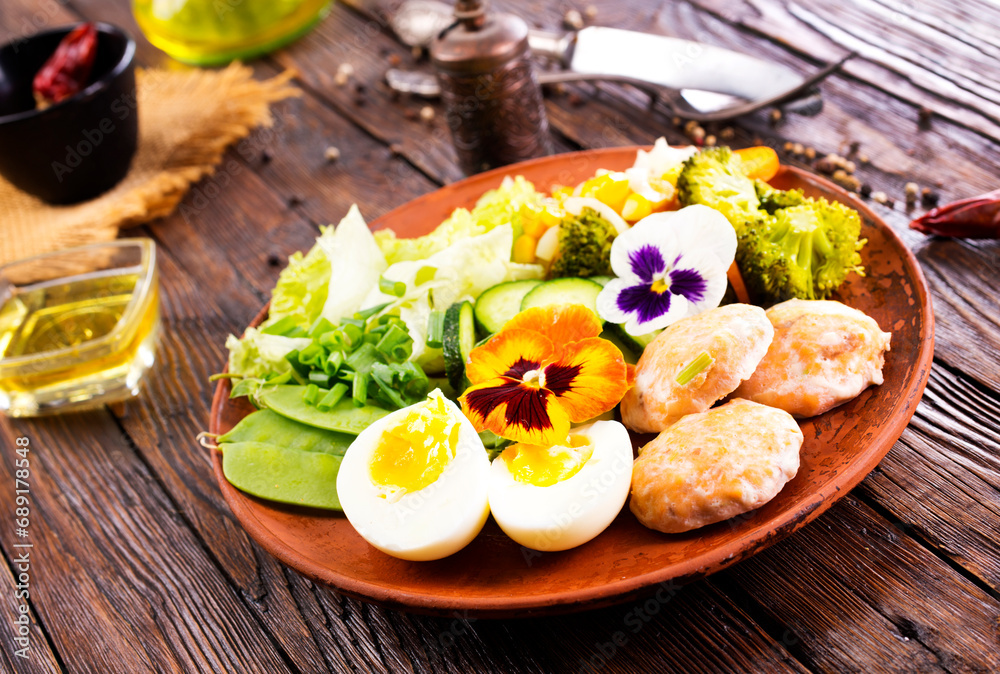 Fried salmon cutlets on a plate with vegetables and boiled eggs