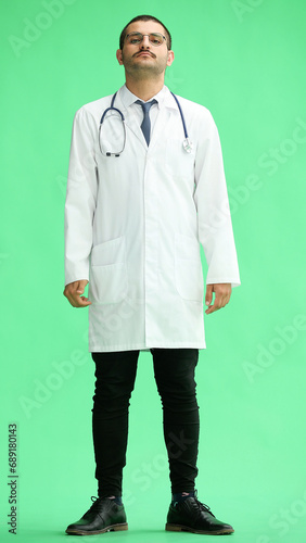 male doctor in a white coat on a green background smiling in full length