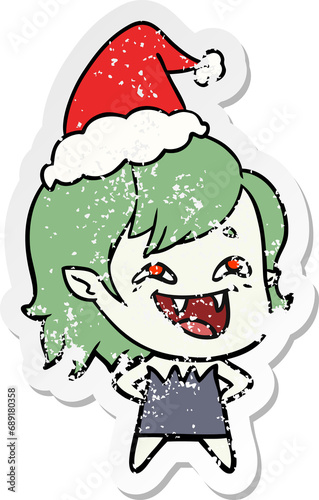 hand drawn distressed sticker cartoon of a laughing vampire girl wearing santa hat