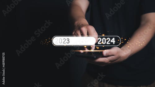 Man Finger pressing on smartphone to loading for changing the year 2023 to 2024. The new year 2024 is loading. Businessman pressing 2024 start up business. Concept of new year.