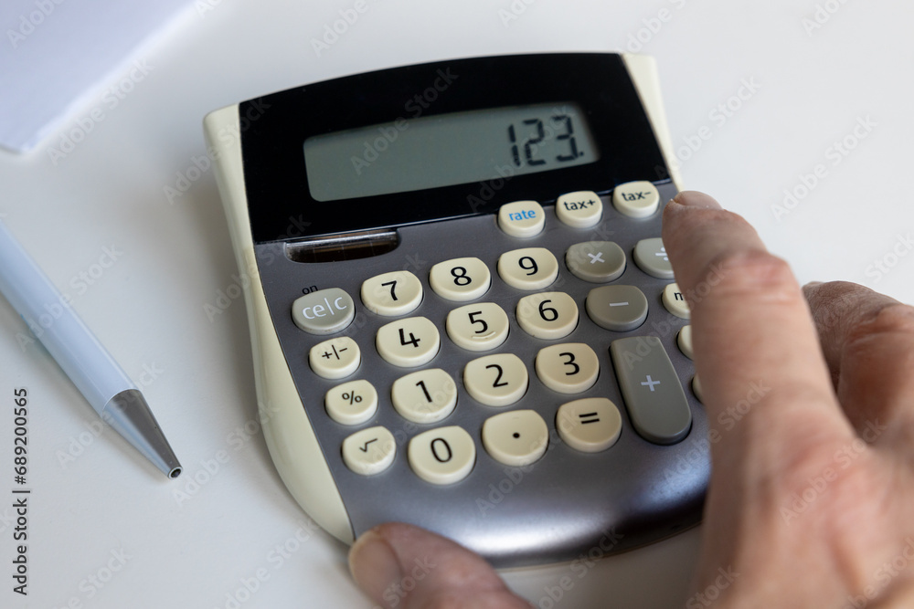 Close up of a calculator with hand and pen and paper Close up of a calculator with hand and pen and paper