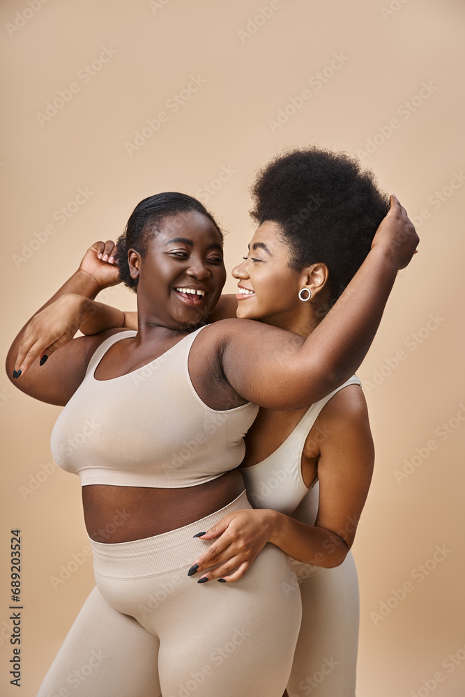 cheerful african american girlfriends in lingerie having fun while posing on beige, curvy beauty cheerful african american girlfriends in lingerie having fun while posing on beige, curvy beauty