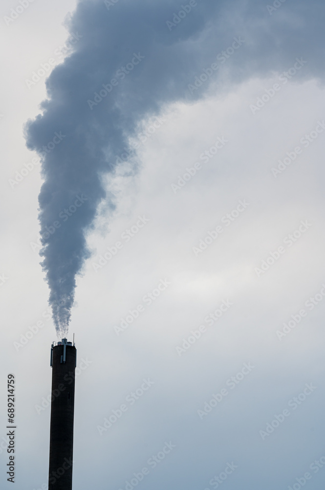 High chimney with pillar of smoke against grey sky High chimney with pillar of smoke against grey sky