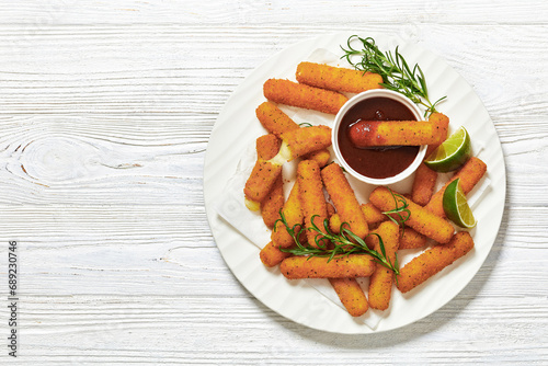 fried mozzarella sticks with sauce on white plate photo