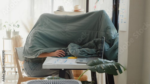 Night owl Young Asia girl development programmer use blanket cover need dim light concentrate create coding program database on computer at house office. Workaholic suffering mental health concept. photo