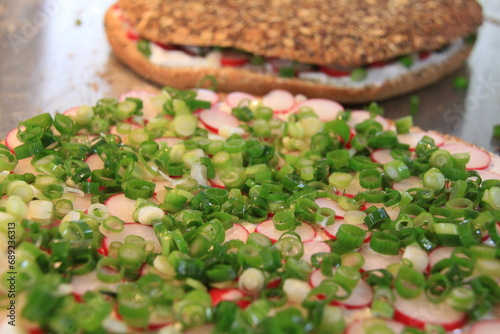 round healthy multi seed bread with fresh cheese, spring onion rings and red radish slices photo