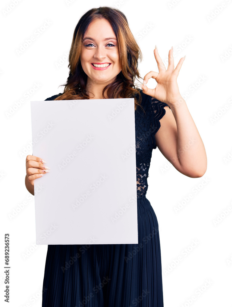 Young beautiful caucasian woman holding cardboard banner with blank space doing ok sign with fingers, smiling friendly gesturing excellent symbol Young beautiful caucasian woman holding cardboard banner with blank space doing ok sign with fingers, smiling friendly gesturing excellent symbol