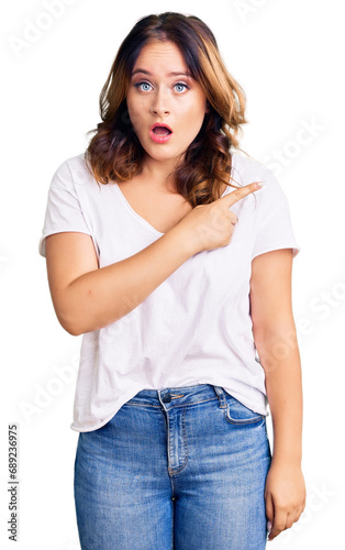Young beautiful caucasian woman wearing casual white tshirt surprised pointing with finger to the side, open mouth amazed expression.