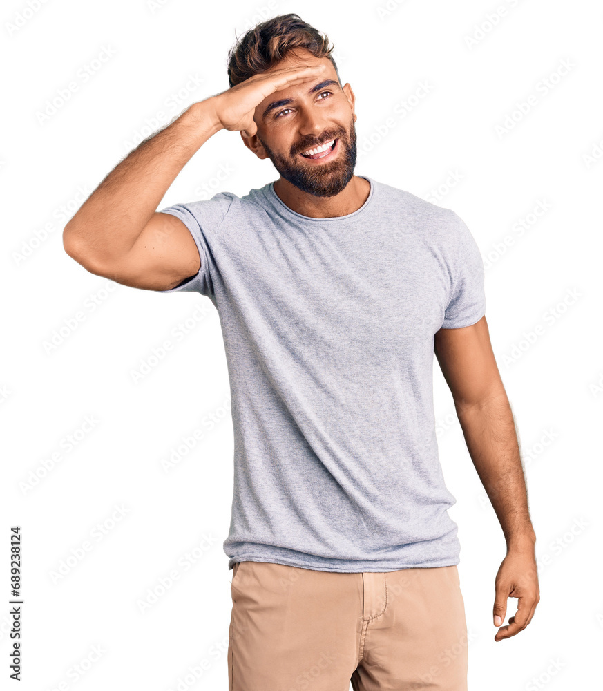 Young hispanic man wearing casual clothes very happy and smiling looking far away with hand over head. searching concept. Young hispanic man wearing casual clothes very happy and smiling looking far away with hand over head. searching concept.