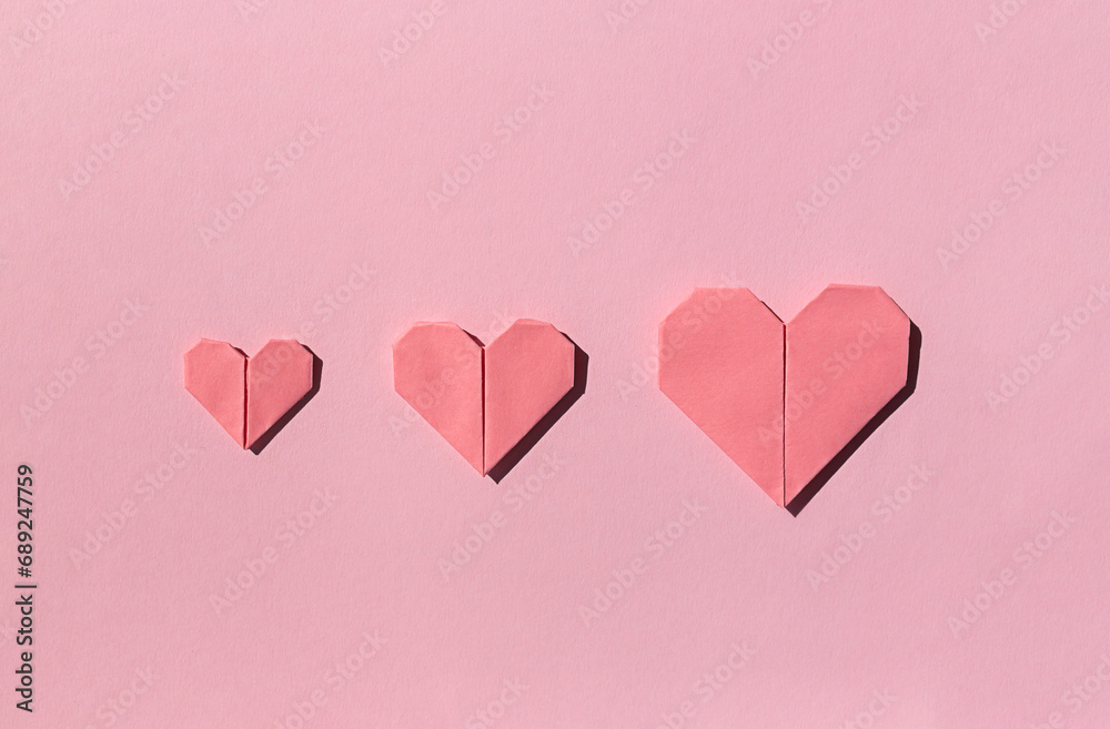 Pink paper origami hearts on the pink background. Valentine's day celebration concept