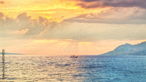 Croatia Sunset a boat sailing under a cloudy sunset with sun rays © jay