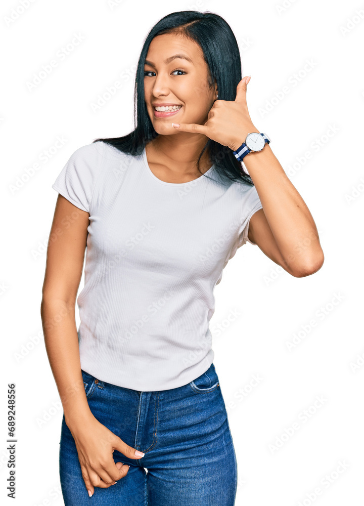 Beautiful hispanic woman wearing casual white tshirt smiling doing phone gesture with hand and fingers like talking on the telephone. communicating concepts. Beautiful hispanic woman wearing casual white tshirt smiling doing phone gesture with hand and fingers like talking on the telephone. communicating concepts.