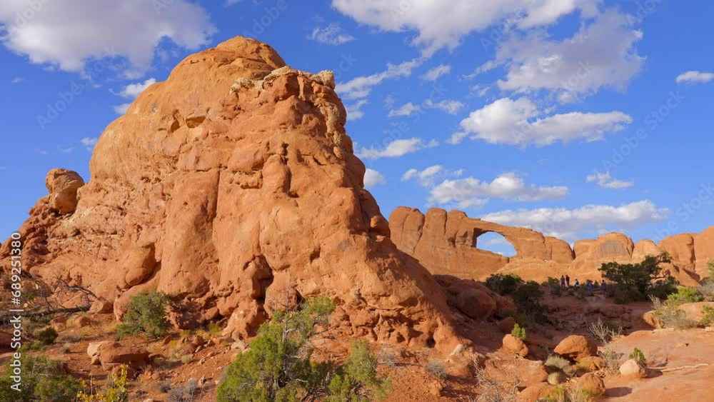 Establishing shot of mountain trail with red rocks background in Sky Arch, Arches National Park, Utah, North America. Day time on October 2023. Still camera view. ProRes 422 HQ. Establishing shot of mountain trail with red rocks background in Sky Arch, Arches National Park, Utah, North America. Day time on October 2023. Still camera view. ProRes 422 HQ.