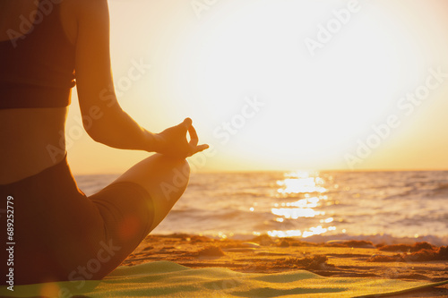 Close up of woman's hand practicing yoga, meditation in lotus position on the beach, feeling so comfortable and relaxing on vacation with golden light, healthy concept