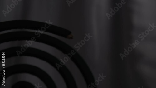 Bringing the mosquito repellent coil closer to the camera. Silhouette of a spiral-shaped mosquito repellent coil. Dispersing incense to repel mosquitoes. 4K video footage.  photo