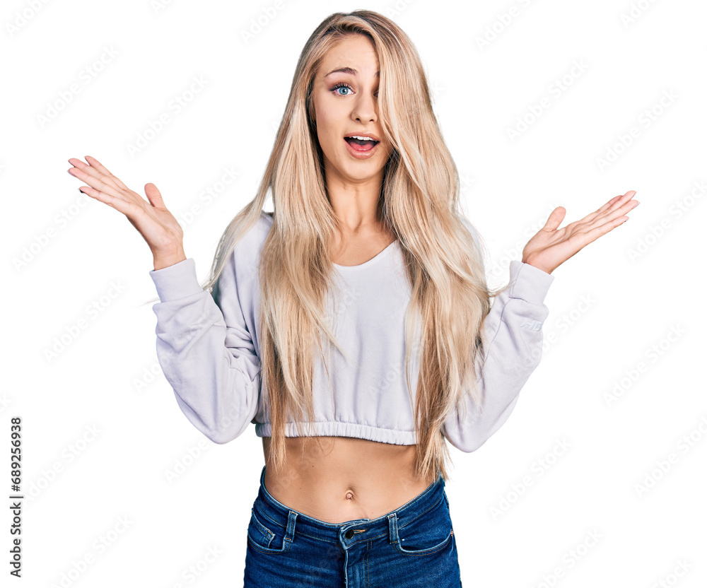 Beautiful young blonde woman wearing casual white sweater celebrating crazy and amazed for success with arms raised and open eyes screaming excited. winner concept