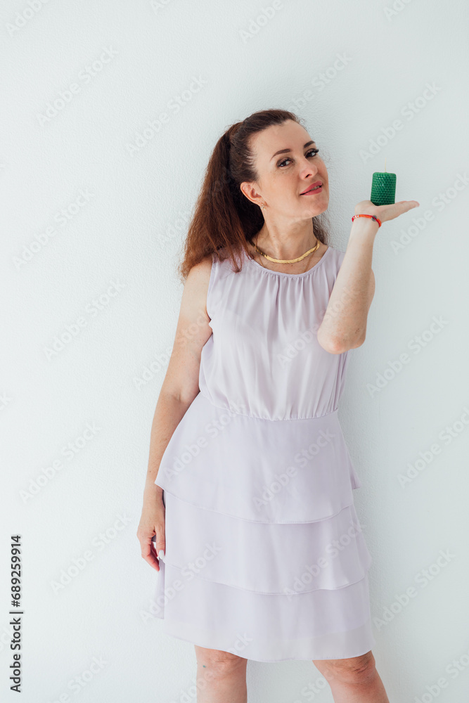 Beautiful brunette woman holding a green candle in her hands Beautiful brunette woman holding a green candle in her hands