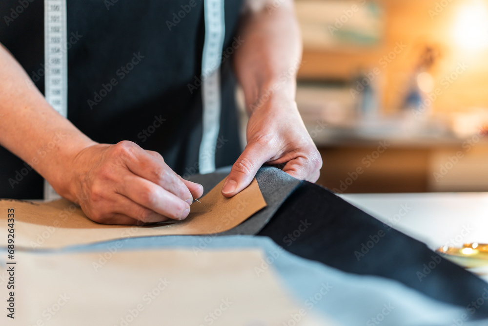 Fashion designer putting pins into pattern and fabric