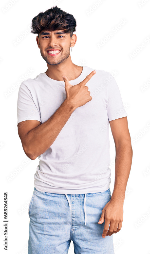Young hispanic man wearing casual clothes cheerful with a smile of face pointing with hand and finger up to the side with happy and natural expression on face Young hispanic man wearing casual clothes cheerful with a smile of face pointing with hand and finger up to the side with happy and natural expression on face