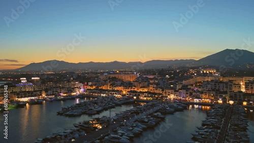 Establishing aerial panoramic view of Puerto Banus marina luxury port Marbella illuminated, Costa del Sol coastline Spain at blue hour. Travel vacation holidays in Spain photo