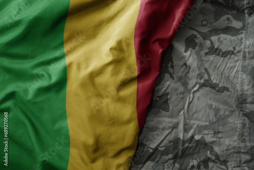 waving flag of mali on the old khaki texture background. military concept.