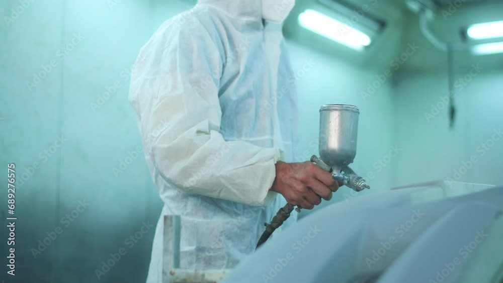 Caucasian man is using painting gun in repair mechanic painting shop Caucasian man is using painting gun in repair mechanic painting shop