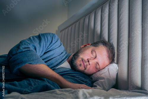 a young man sleeping in a bed at night