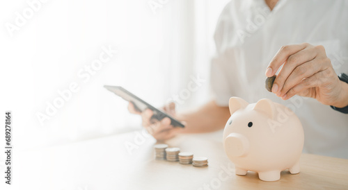 a man hand putting money coin into piggy for saving money wealth and financial concept. Businessman is calculating income and return on investment.