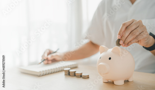 a man hand putting money coin into piggy for saving money wealth and financial concept.