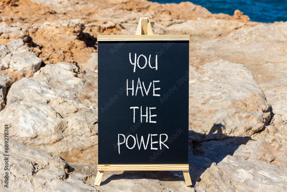 Fototapeta premium You have the power symbol. Concept word You have the power on beautiful black chalk blackboard. Beautiful red stone blue sea background. Business motivational you have the power concept. Copy space.